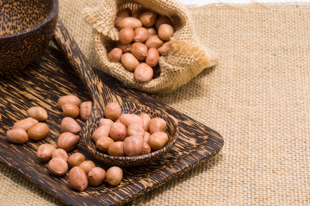 No shell dry peanut in wooden spoon and sack. Focus at nut in spoonの写真素材