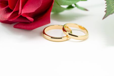 Wedding rings and artificial rose on white background, horizontally Selective focusの写真素材