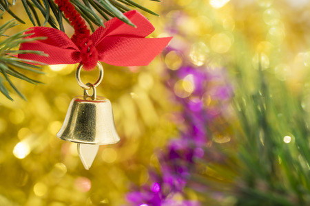 Christmas bell ornament hang on Christmas tree branch with yellow bokeh backgroundの写真素材