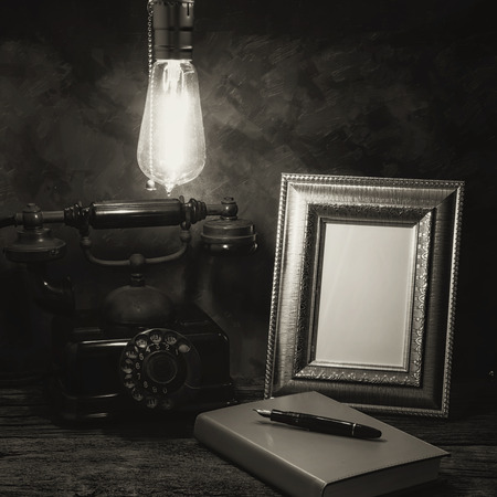 Still life of vintage telephone with picture frame and diary on table, Black and White imageの写真素材