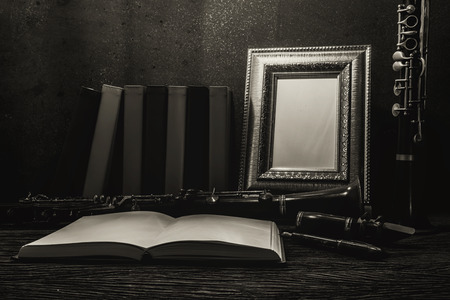 Still life of picture frame on wooden table with clarinet, black and white image