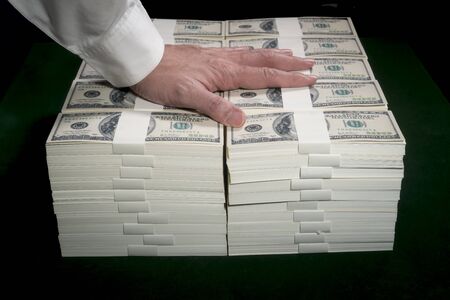Stacks of one million US dollars in hundred dollar banknotes on green table.の写真素材