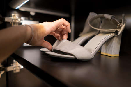 Picking silver Bare back foot shoes off the rack, concept of fashion shoe and lady lifestyle.の写真素材