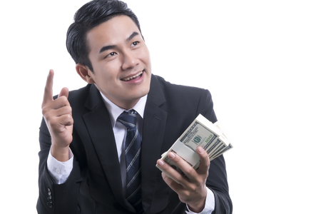 Portrait of the Rich Successful Businessman hold many dollars in hand is smiling and pointing fingeron white background and copy space
の写真素材