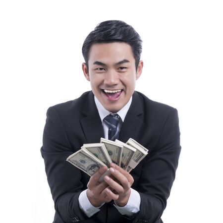 Happy young businessman in black suit holding dollars in hand and smiling with successful on a white background, concept rich, success and businessの写真素材