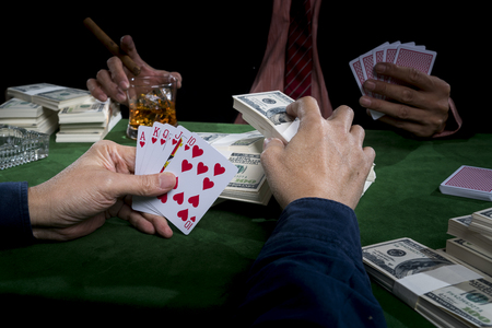 The gambler is putting some banknote into the piles of bets, When he thinks he is the winner in this game, on green table and black backgroundの写真素材