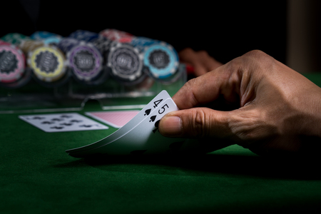 A hand holding the cards show face values nine to win a blackjack game on green table and blurry...