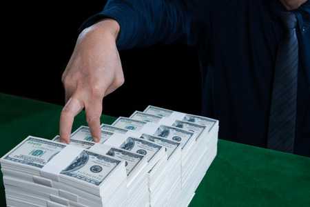 The hand of businessman use finger is walk step on stack of dollars growing in business, on green table concept of growth, finance, competition and success businessの写真素材