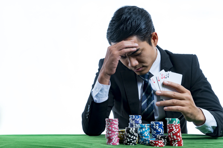 The young gambler used a hand off the face with action stress when he defeated in poker game, on white background and copy space with casino concept
の写真素材