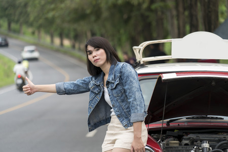 Asian lovely girl thumbs up on a symbol for needs help after car breakdown and parked on the roadside, Travel conceptの写真素材