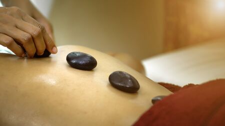close up and slow motion shot of Thai masseur massage place the Hot stone on backbone of pretty...