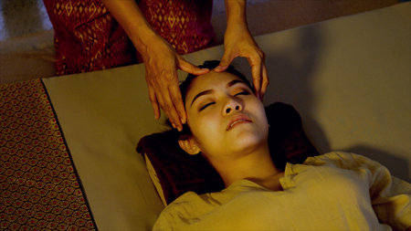 close up shot with Thai massage session for head and face of beautiful woman, Treatment of headache with pressing roll on the head, eyebrows, and face,Thai massage conceptの写真素材