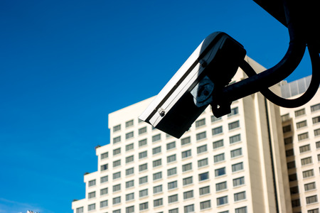 The Surveillance Security Camera, the closed circuit television or CCTV for protection system under the bridge and blur background with building and blue sky, copy spaceの写真素材