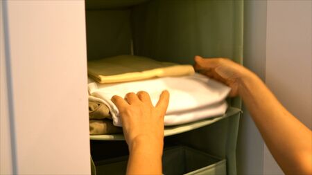 female hands were brought stack of T-shirts folded neatly and put into the hanging closet,