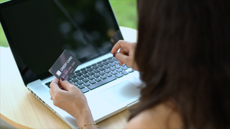 close up shot, top view to behind of hands of female is typing and credit card transaction on laptop with shopping onlineの写真素材