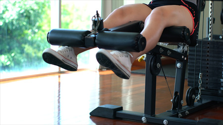 close up shot with two legs of young woman on a weight lifting exercise machine with a leg to leg muscles strong in gymの写真素材