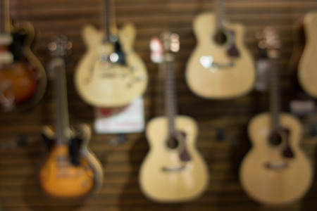 Blurry background with close up image of the guitar hanging on the wall for sale in musical shop with bokeh lightの写真素材