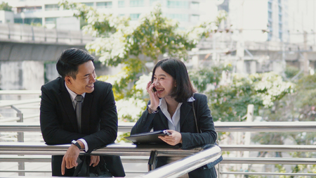 Close up Male and female Asian co-workers are talking and laughing together on the bridge, business conceptの写真素材