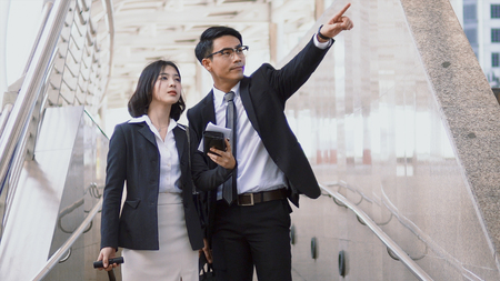 Asian young businessman has route guidance to pretty woman, He raised a finger pointing the way to herの写真素材