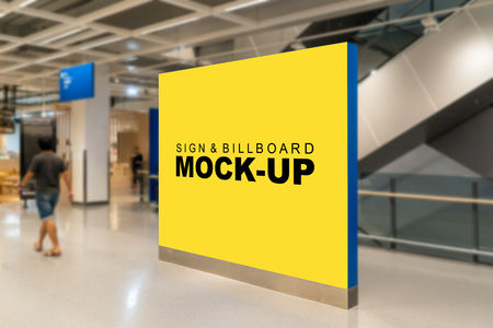 Mock up large blank yellow screen billboard with clipping path placed near the escalator in building and blurred passenger walking, perspective empty space for advertising or informationの写真素材