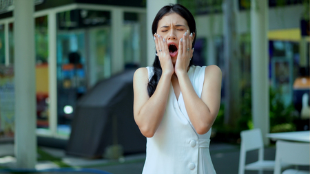 The pretty woman standing and used the hand to close her mouth while yawning sleepy and copy spaceの写真素材