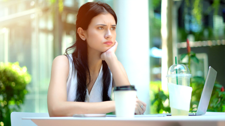 Close up the young woman sitting and her chin on hand with feeling stressed and frustratedの写真素材