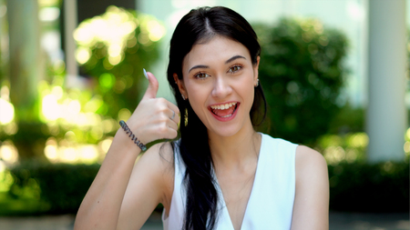 Close up and selective focus at a lovely young woman has big smiling and show movement with blurred thumbs up to cameraの写真素材
