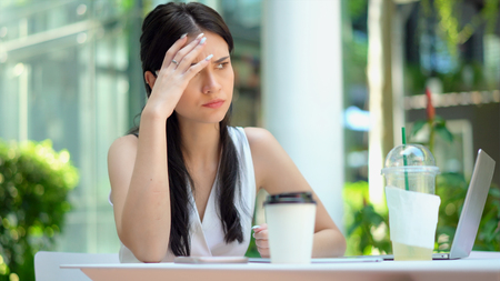 Close up the young woman sitting and hold the head on hand with feeling stressed and boringの写真素材