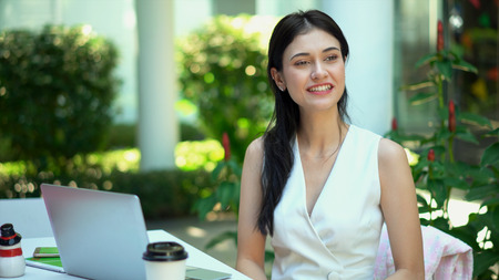 Close up the young pretty woman happiness in the garden, has laptop and shopping bag on tableの写真素材