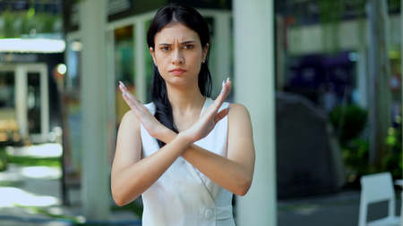 The young woman standing with looking camera and she lifted two arms cross, she face feeling in seriouslyの写真素材