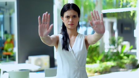 The young woman standing with cross arms looking camera and she lifted two hands for stop and seriouslyの写真素材