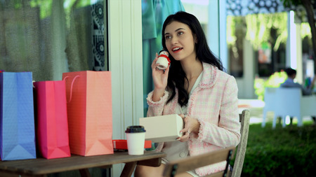Young pretty woman holding a Santa doll with happiness, many shopping bag on tableの写真素材