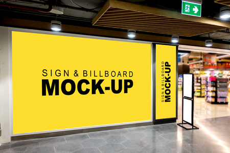 Mock up large blank yellow screen billboard and vertical signboard and white screen on stand board with clipping path in mall and blurred shelf in background, empty space for advertising informationの写真素材
