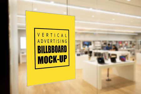 Mock up blank vertical yellow screen billboard or signboard with clipping path on the glass panel of modern store in the shopping mall, empty space for message or media advertisement indoors.の写真素材