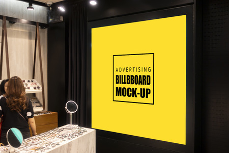 Mock up square shape advertising billboard with clipping path on the wall, yellow screen empty space for advertisement or promotion price in glasses shop, blurred people in backgroundの写真素材