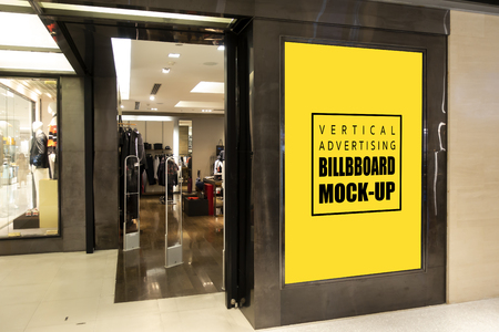 Mock up vertical advertising billboard with clipping path on panel,  yellow screen empty space for advertisement on panel near entrance the fashion clothing shop in shopping mallの写真素材