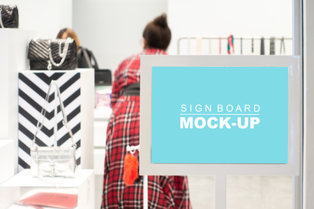 Mock up horizontal blank signboard with clipping path show discount in shop bag ladies at shopping mall, blurred female customer, Blue screen in white frame on panel for insert text or advertisingの写真素材