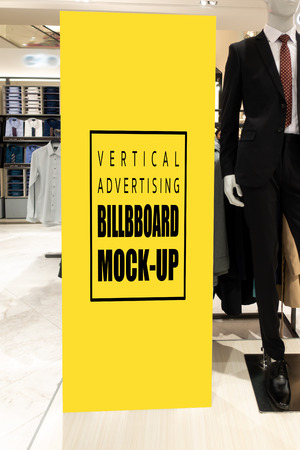 Mock up vertical blank billboard with clipping path to show promotion or discount in men's suit and clothing shop, tall yellow screen empty space for insert text or advertising in shopping mallの写真素材