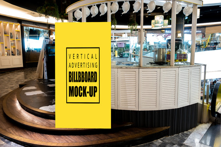 Mock up vertical blank billboard standing at front of tea booth in shopping mall, Yellow screen empty space for insert text or advertisingの写真素材