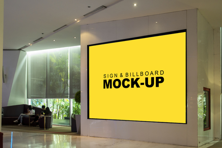 Mock up perspective the horizontal blank billboard in black frame on the wall at walkway of shopping mall , Yellow screen empty space for insert text or advertisingの写真素材