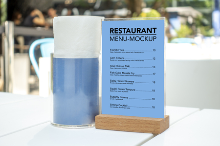 Mock up menu frame standing on white table in restaurant  , the tissue box placed nearly, blue empty space for insert text menu or advertising or announcement promotionの写真素材