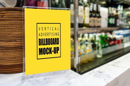 Mock up vertical advertising signboard in acrylic frame   in super store, blurred background with many kinds of beverage bottle on  shelf, empty space for insert advertisingの写真素材