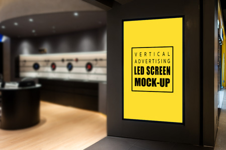 Mock up blank vertical LED screen  at the entrance of IT Shop in shopping mall, Yellow screen empty space for insert media to promotion with modern decorationの写真素材