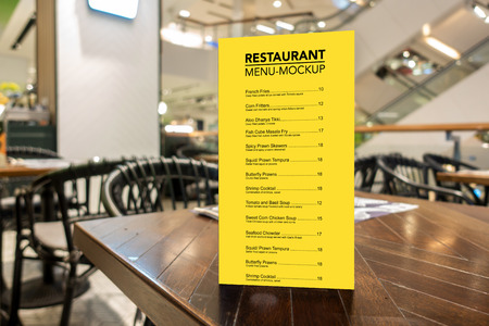 Mock up vertical blank menu in coffee shop in acrylic frame placed on wooden table, yellow screen empty space for insert list menu and priceの写真素材