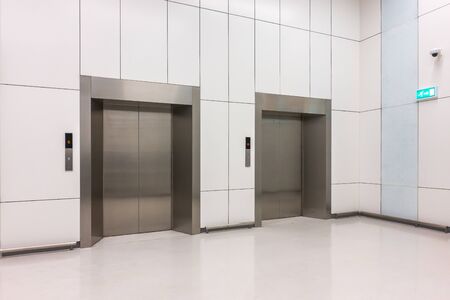 Perspective image of modern steel elevator cabins with closed doors in the business lobby