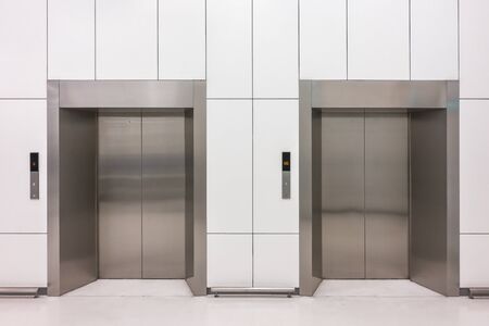 Front view of modern steel elevator cabins with closed doors at business lobbyの写真素材