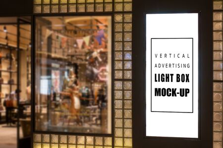 Mock up vertical light box on glass panel of lady bag shop in mall  , empty space for insert media advertising or informationの写真素材