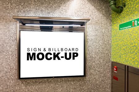 Mock up blank horizontal billboard on glass showcase with metal frame with clipping path at metro station near Fire extinguisher point, empty space for insert advertising or informationの写真素材