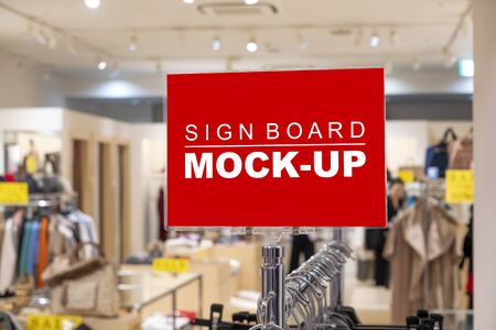 Mock up blank signboard with clipping path on the clothesline in cloths showroom in shopping mall, empty space for insert advertising , discount price or information の写真素材