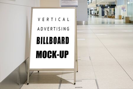 Mock up blank vertical signboard with clipping path on stainless steel stand on walkway in airport terminal, empty space for insert advertising or announcement informationの写真素材